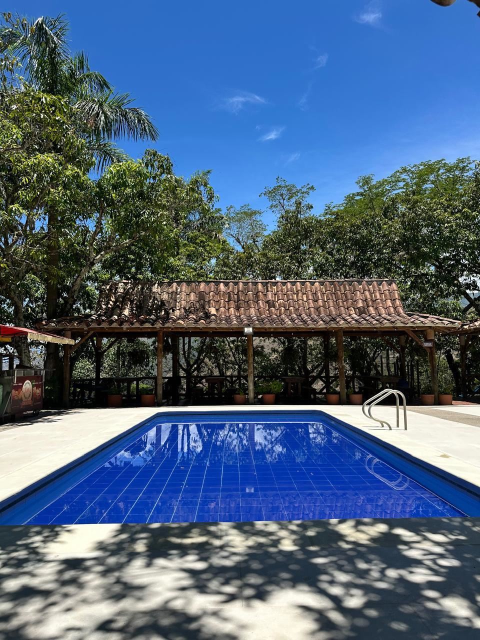 Piscina de niños frente a un kiosco con techo de teja, bajo un cielo despejado