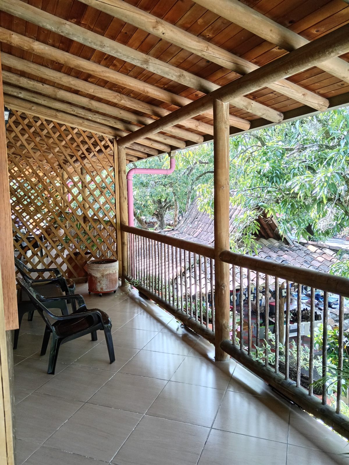 Balcón privado con sillas, techo en madera y vista a los árboles